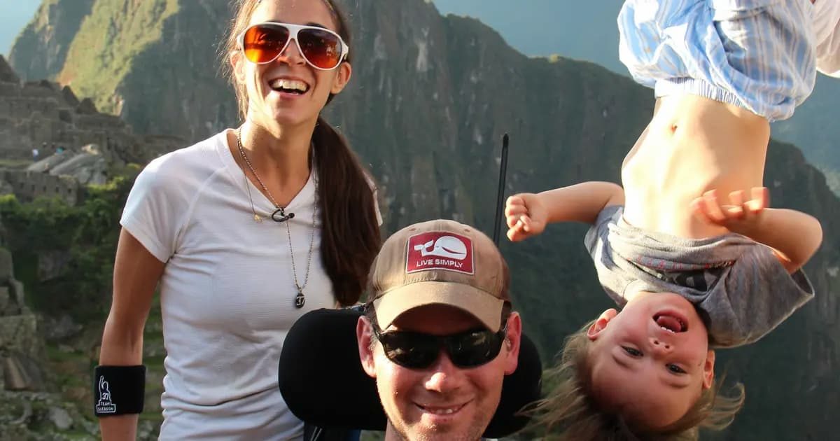 Steve Gleason and his family laughing together on a mountain trail, with a young child upside down and grinning